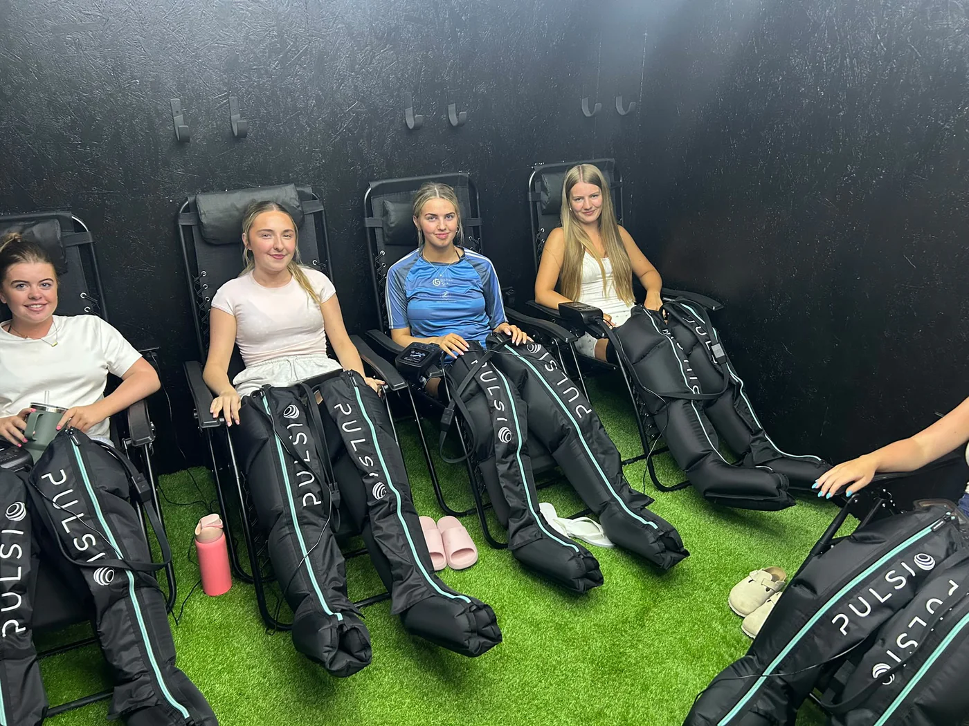 Four women relaxing in reclining chairs wearing compression boots