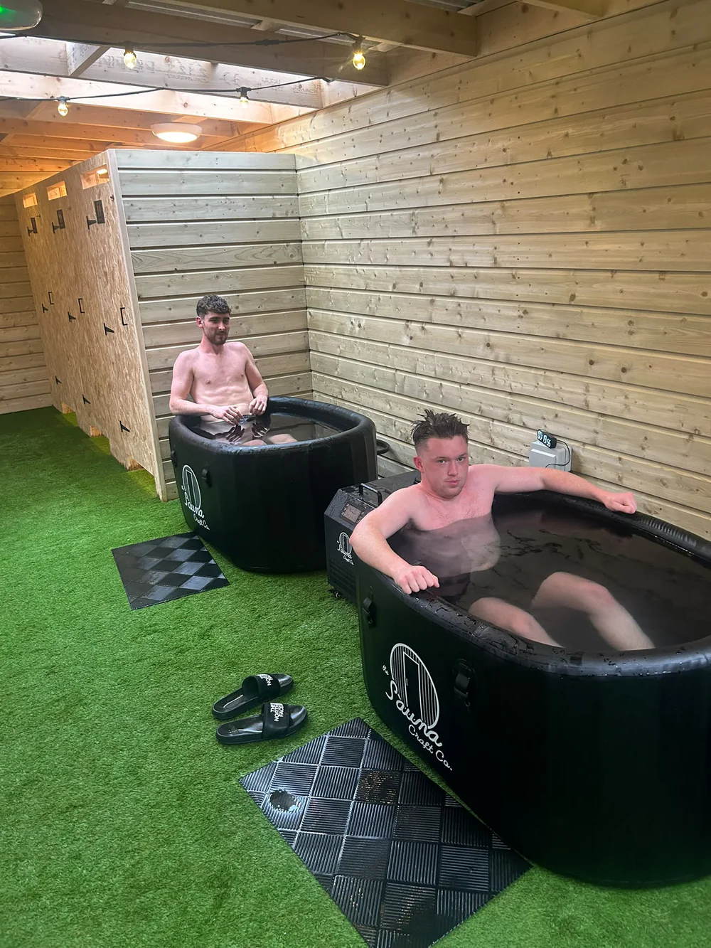 Two people sitting in the black ice baths inside the timber recovery room