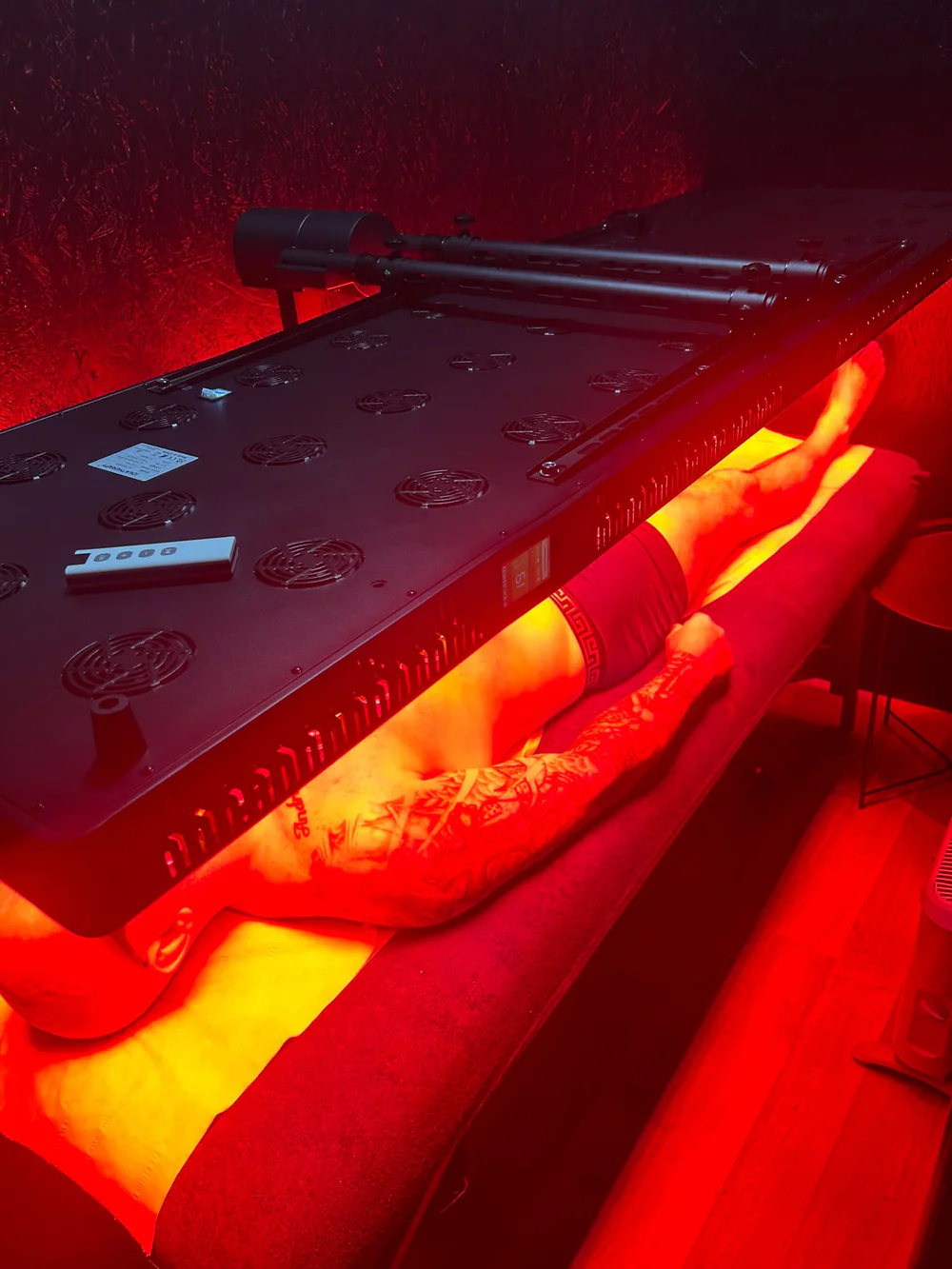Someone lying on the red light therapy bed under the glowing canopy